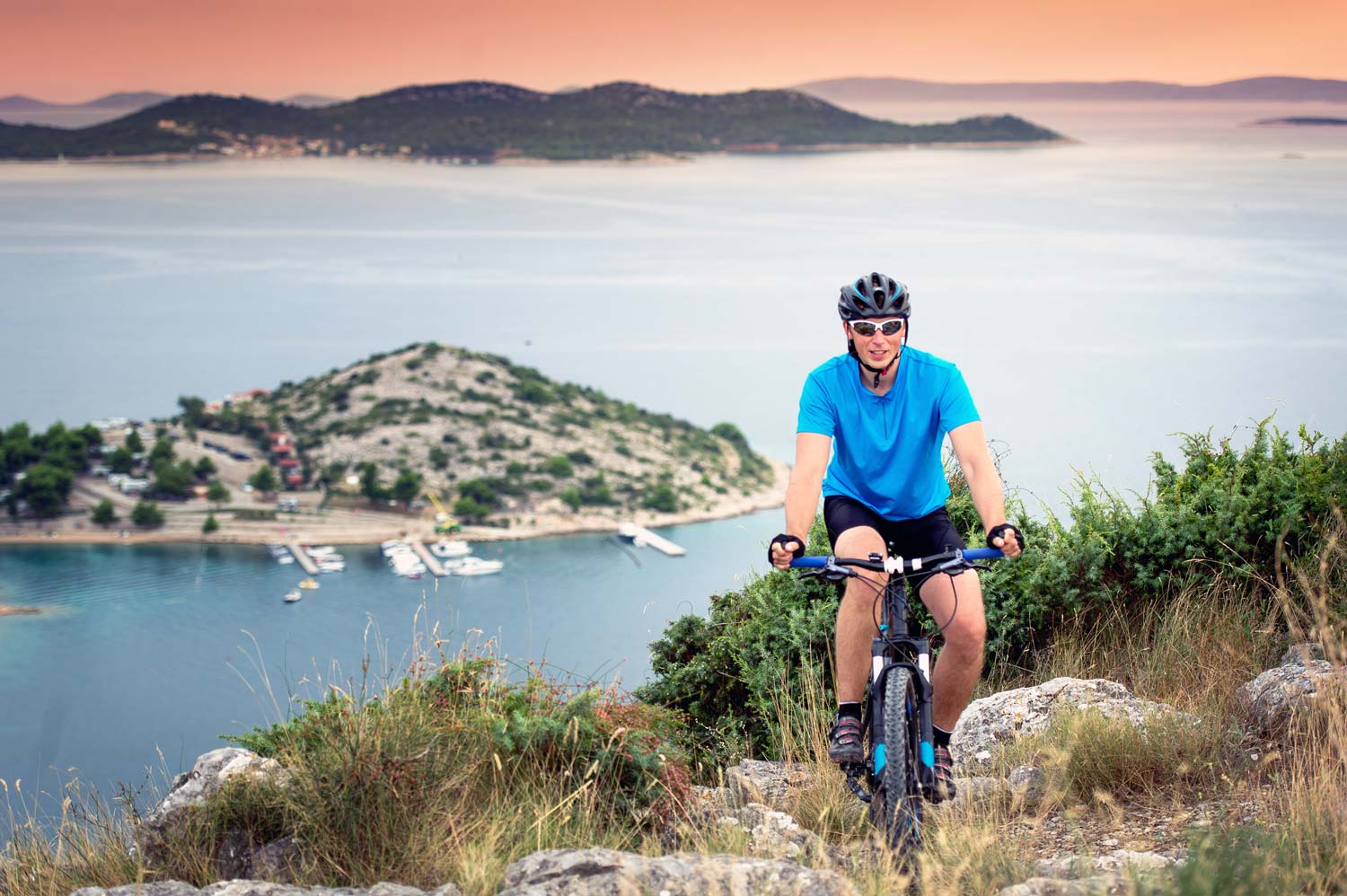 Photo showing a person mountain biking with the sea in the background